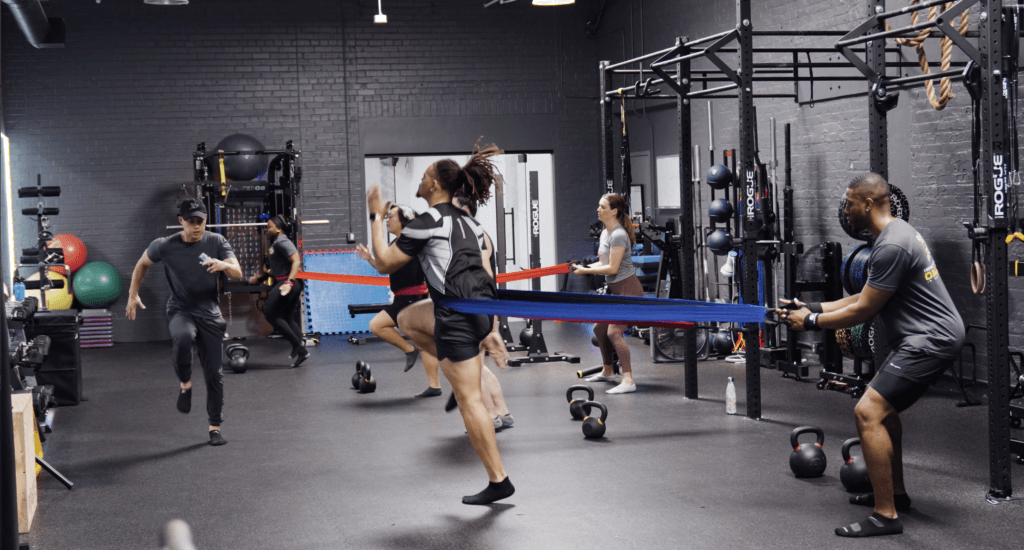 Small group training class using resistance bands on the floor at Impact Fitness Oakland