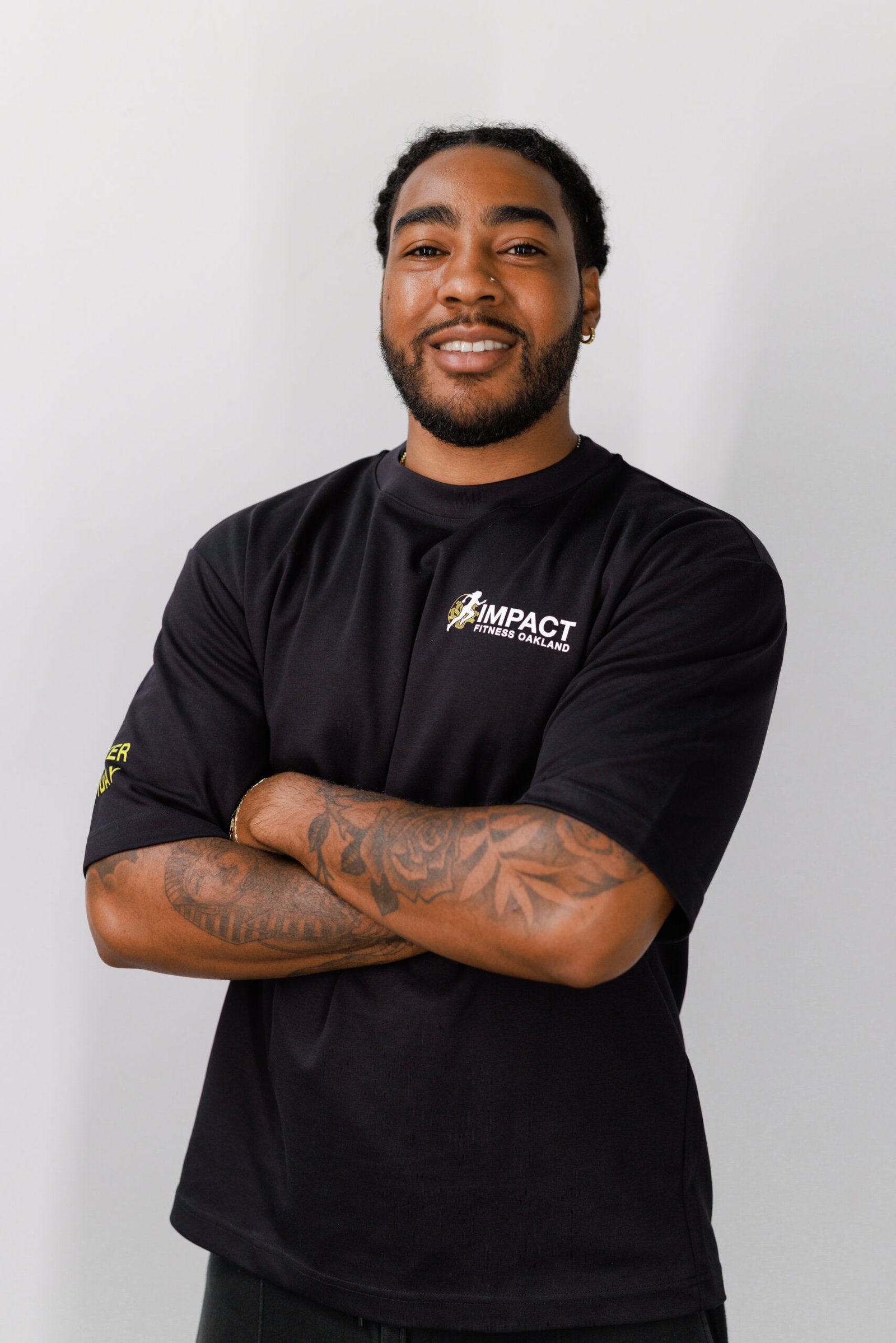 Stanley Arnold-Wright, ISSA-certified personal trainer at Impact Fitness Oakland, arms crossed and smiling