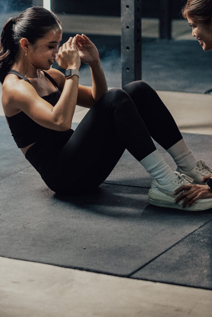 Beginner-friendly personal training at Impact Fitness Oakland — coach supporting a client through floor-based core work in a private Oakland studio