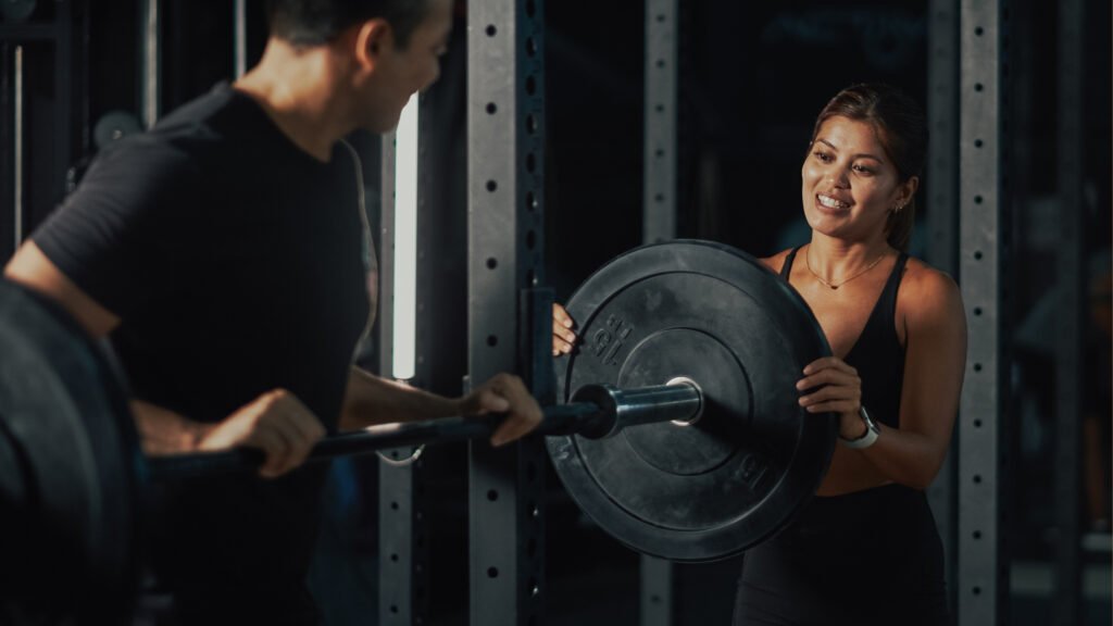 Pain-free personal training in Oakland — coach spotting client through a loaded barbell lift after movement assessment at Impact Fitness Oakland